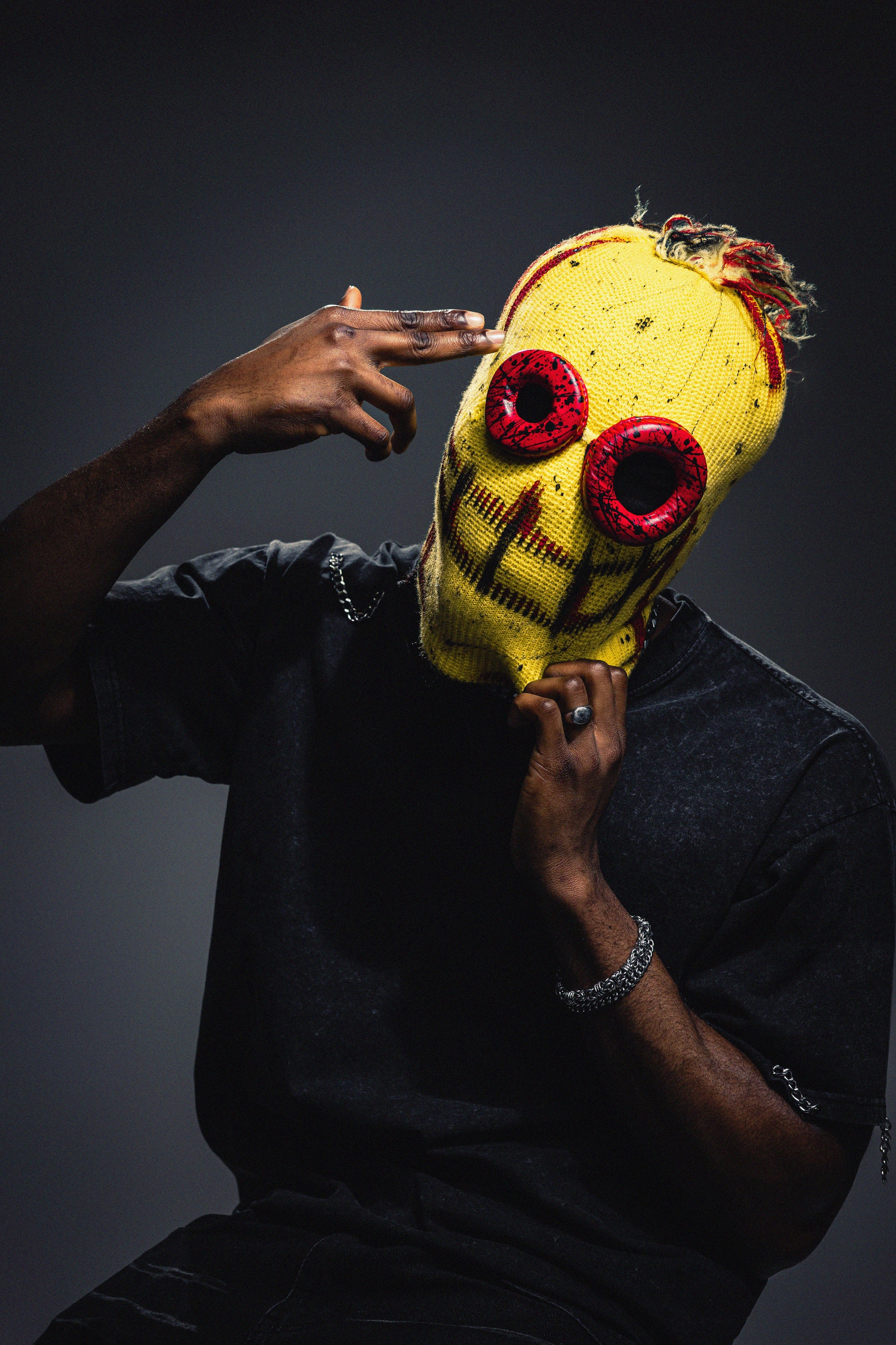 Person wearing a yellow mask with red eyes against a dark background