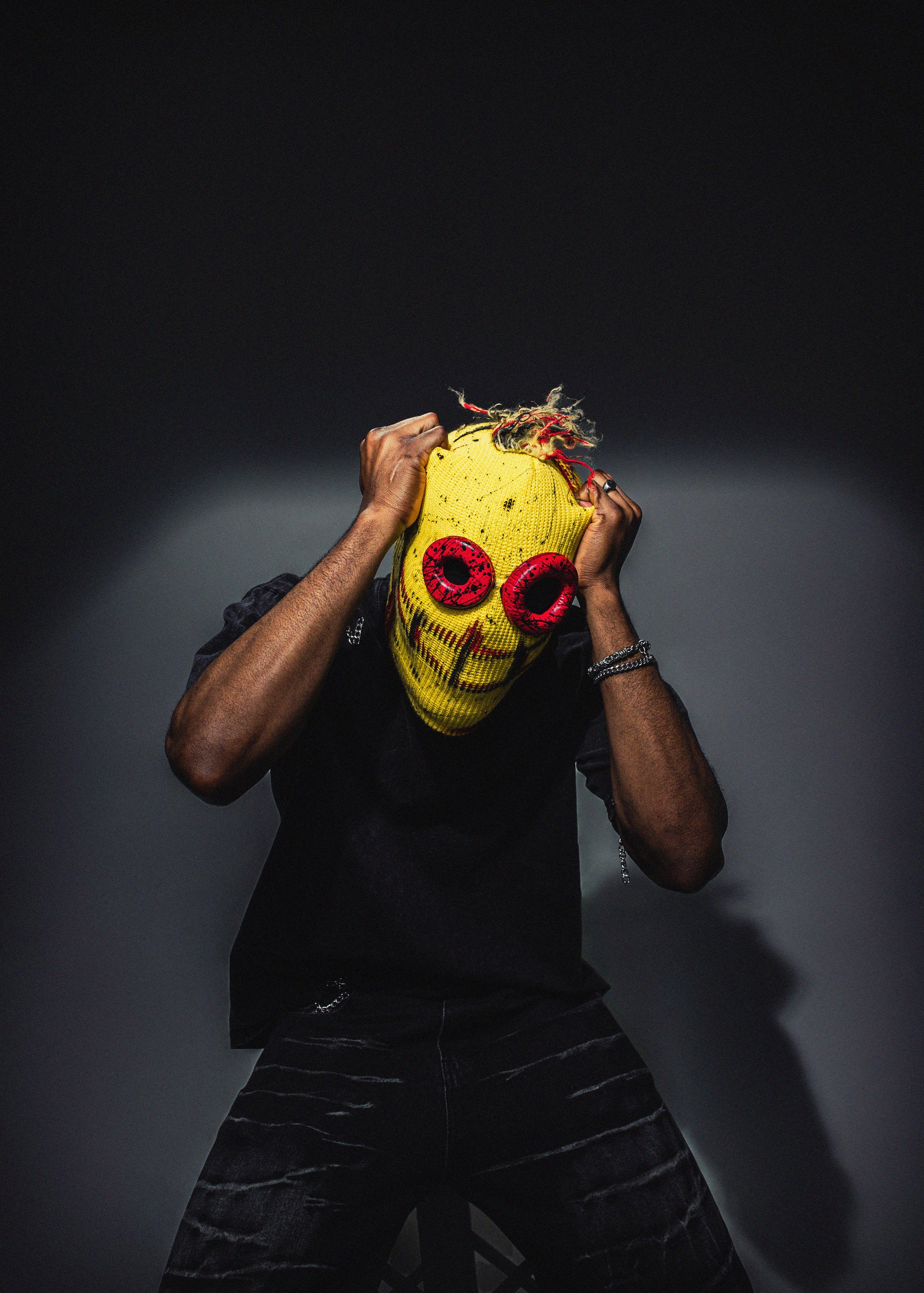 Person wearing a colorful mask with red eyes against a dark background