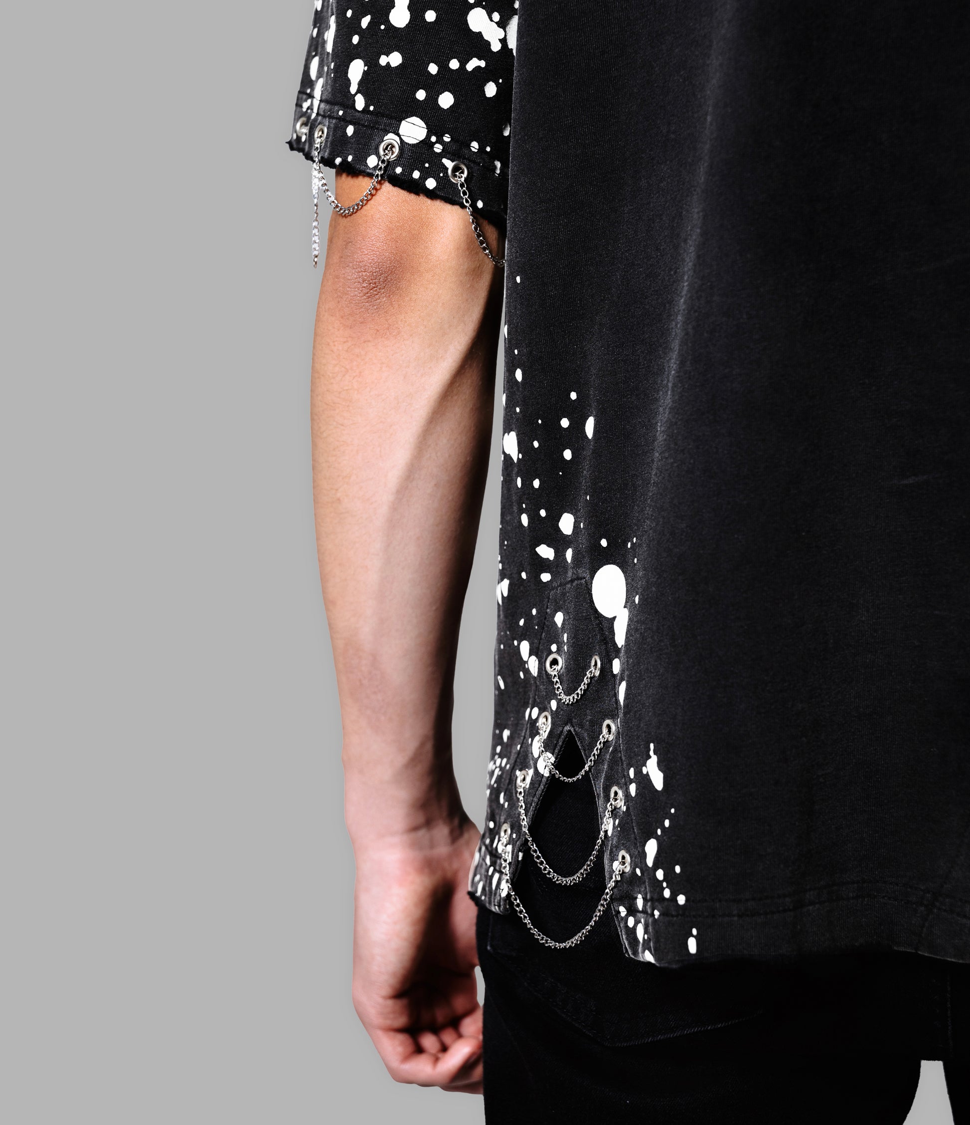 Black t-shirt with white splatter design and silver chain detail on a gray background