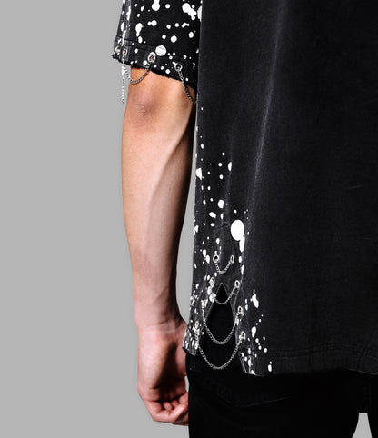 Black t-shirt with white splatter design and silver chain detail on a gray background