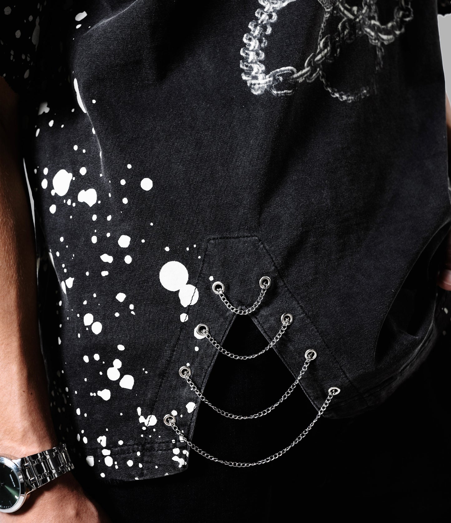 Black shirt with white splatter design and chain details on a gray background