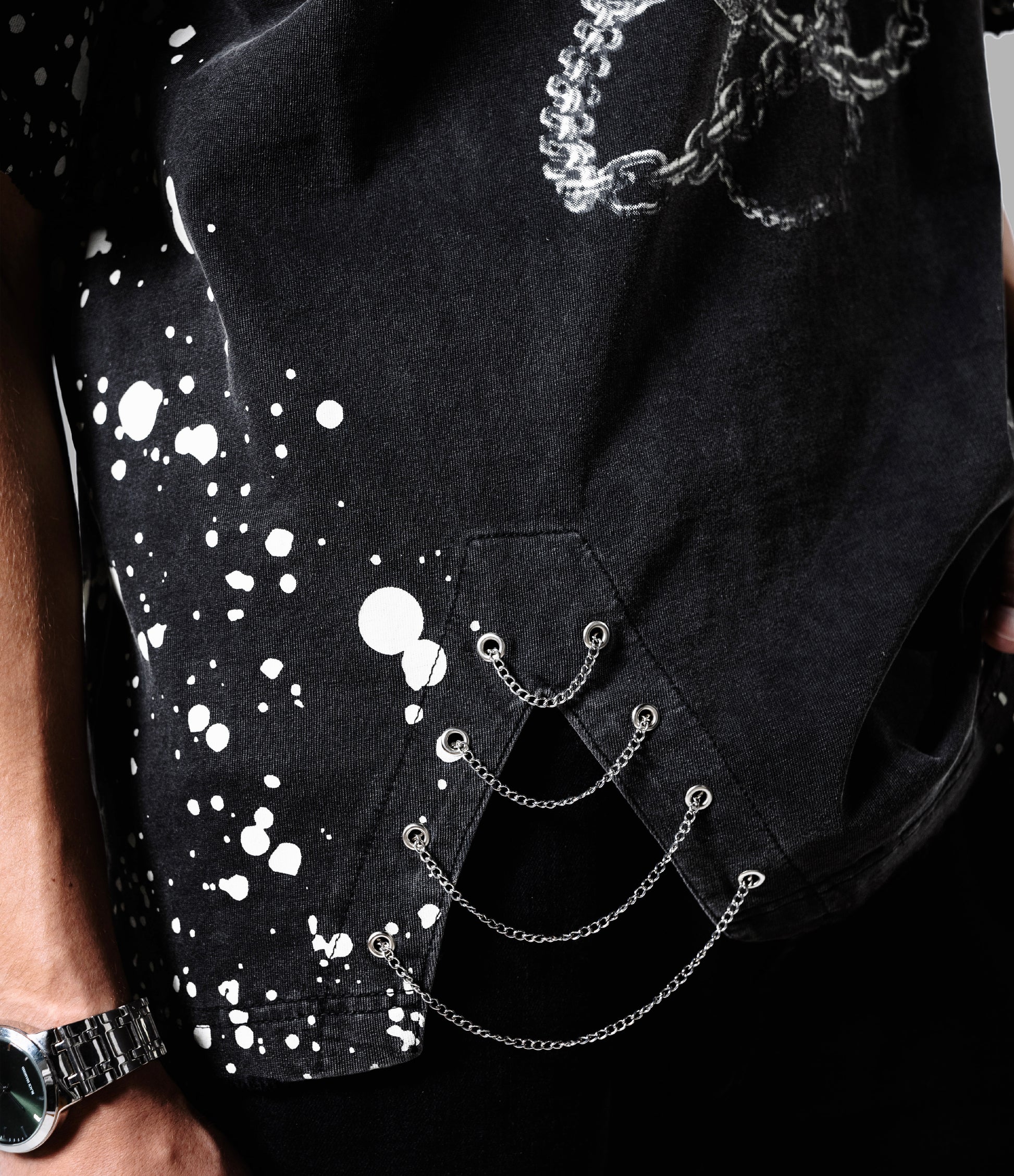 Black shirt with white splatter design and chain details on a gray background