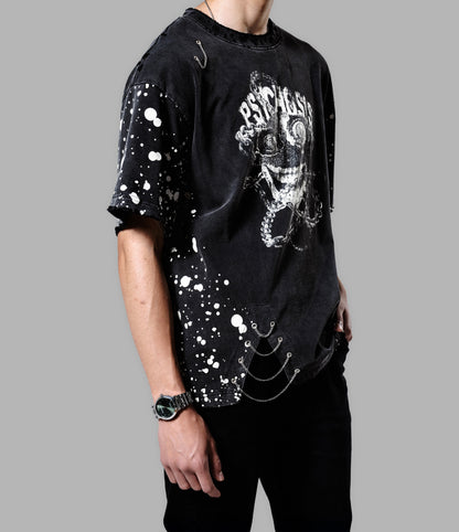 Person wearing a black t-shirt with graphic design and splatter paint effect on a gray background